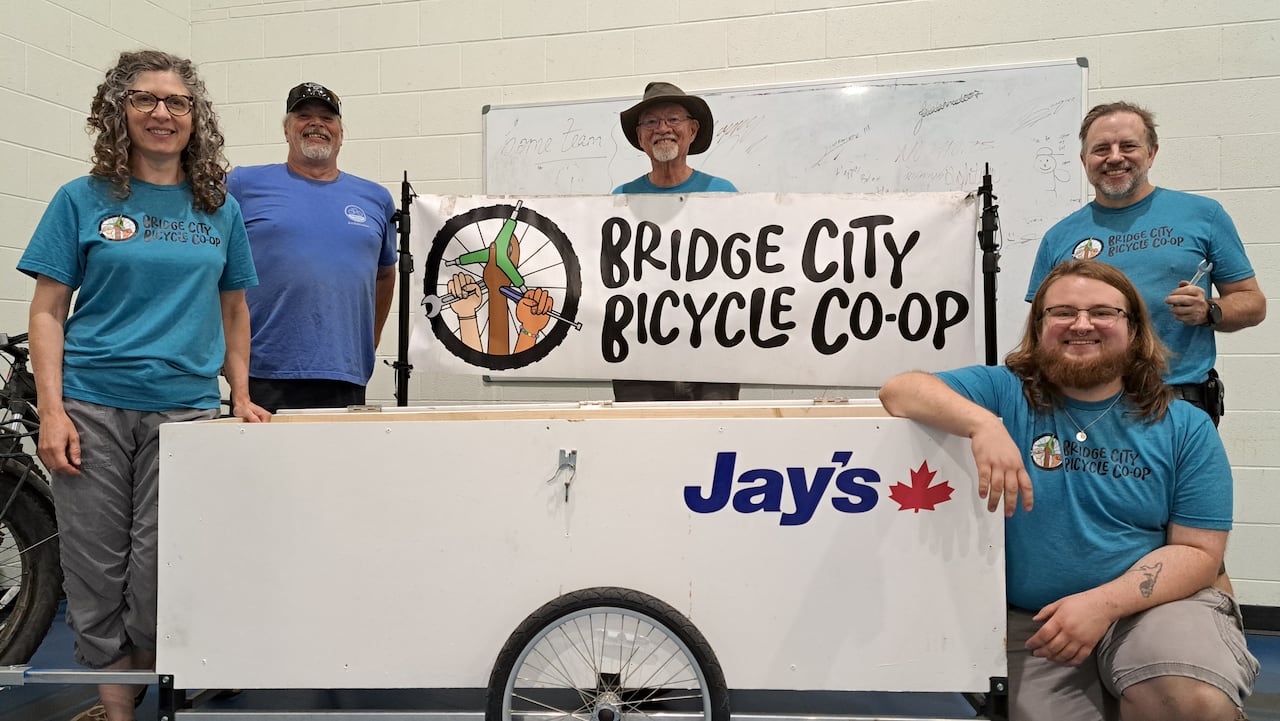 Several people next to a sign for Bridge City Bicycle Co-op