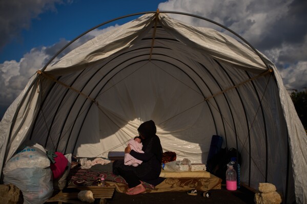 Haifa Kenjo, who fled Israeli airstrikes on the southern suburbs of Beirut, holds her 15-day-old daughter Shiman inside the tent she uses as a shelter and where she gave birth to her in Beirut, Sunday, April 12, 2026. (AP Photo/Emilio Morenatti)