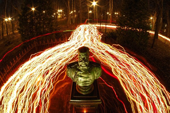 In this long exposure photo, Orthodox believers walk with candles past a bust of the Russian Tsar Alexander III installed near a church during Orthodox Easter midnight service in St. Petersburg, Russia, Sunday, April 12, 2026. (AP Photo/Dmitri Lovetsky)