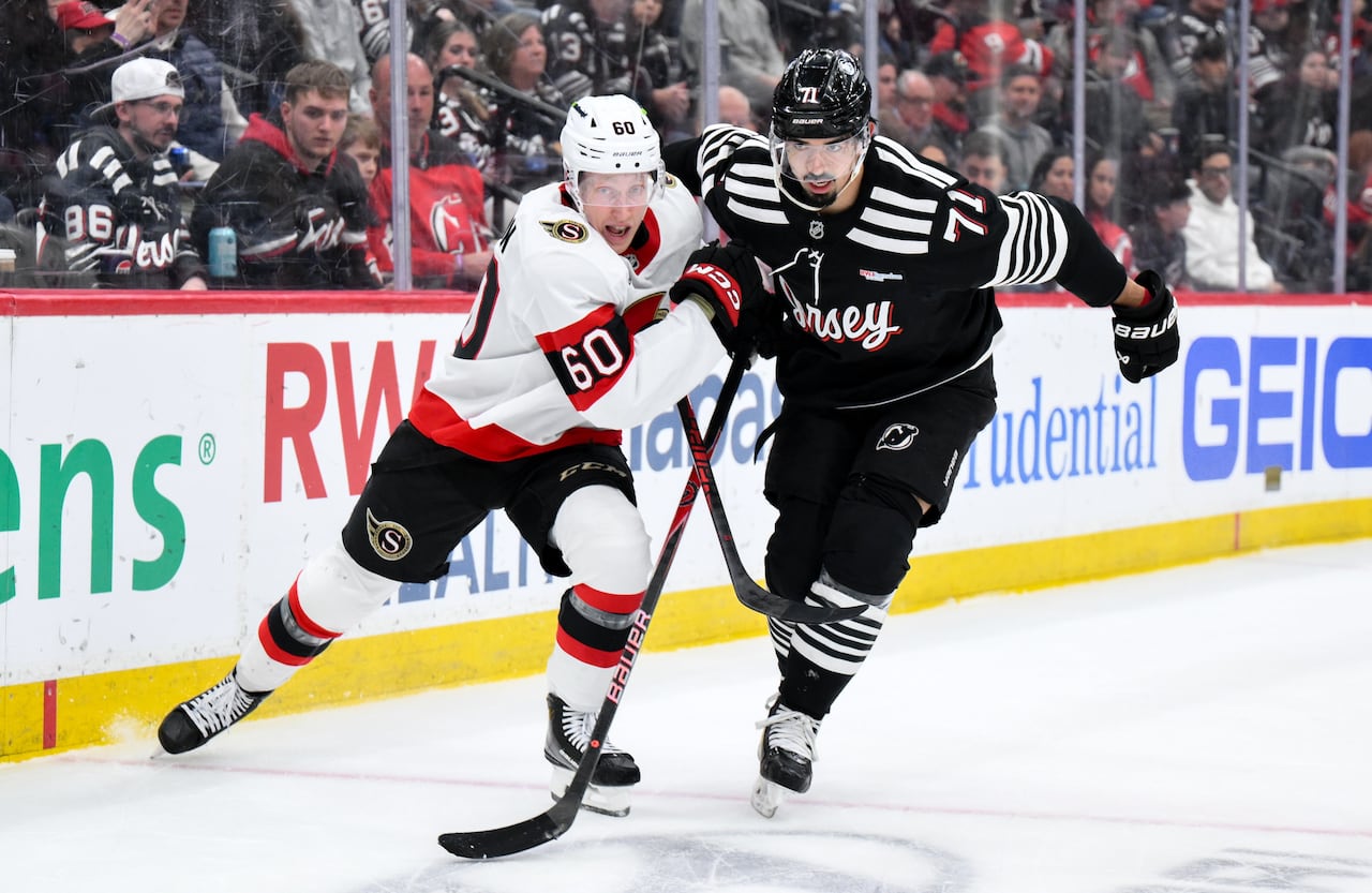 Two hockey players push each other in a puck battle during a game.