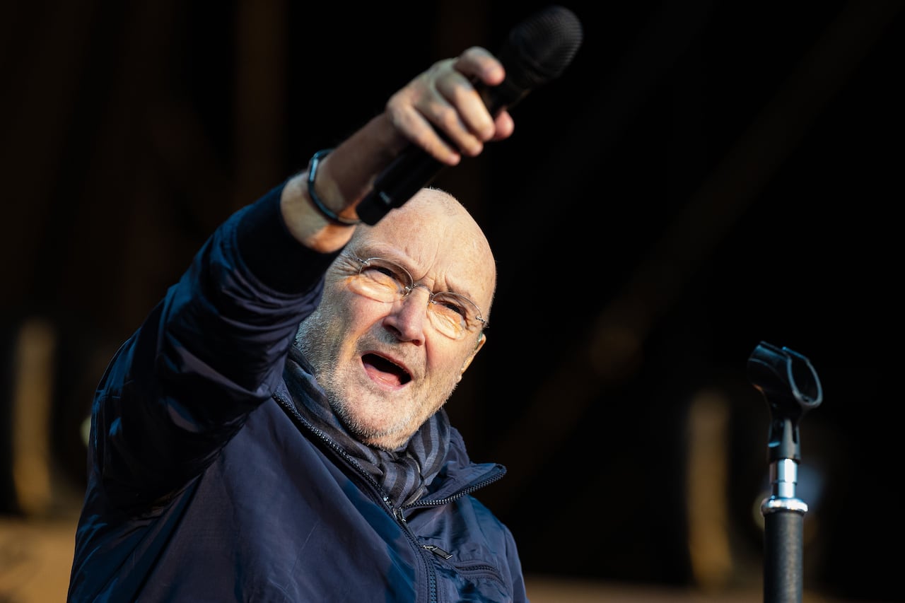 Bald man gestures with microphone on stage