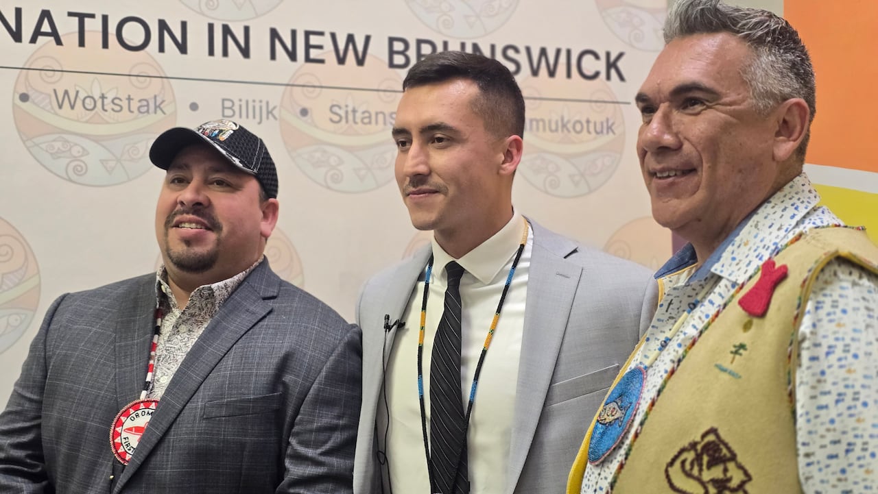 Three men standing side-by-side. Two with suits and one in a brown vest.