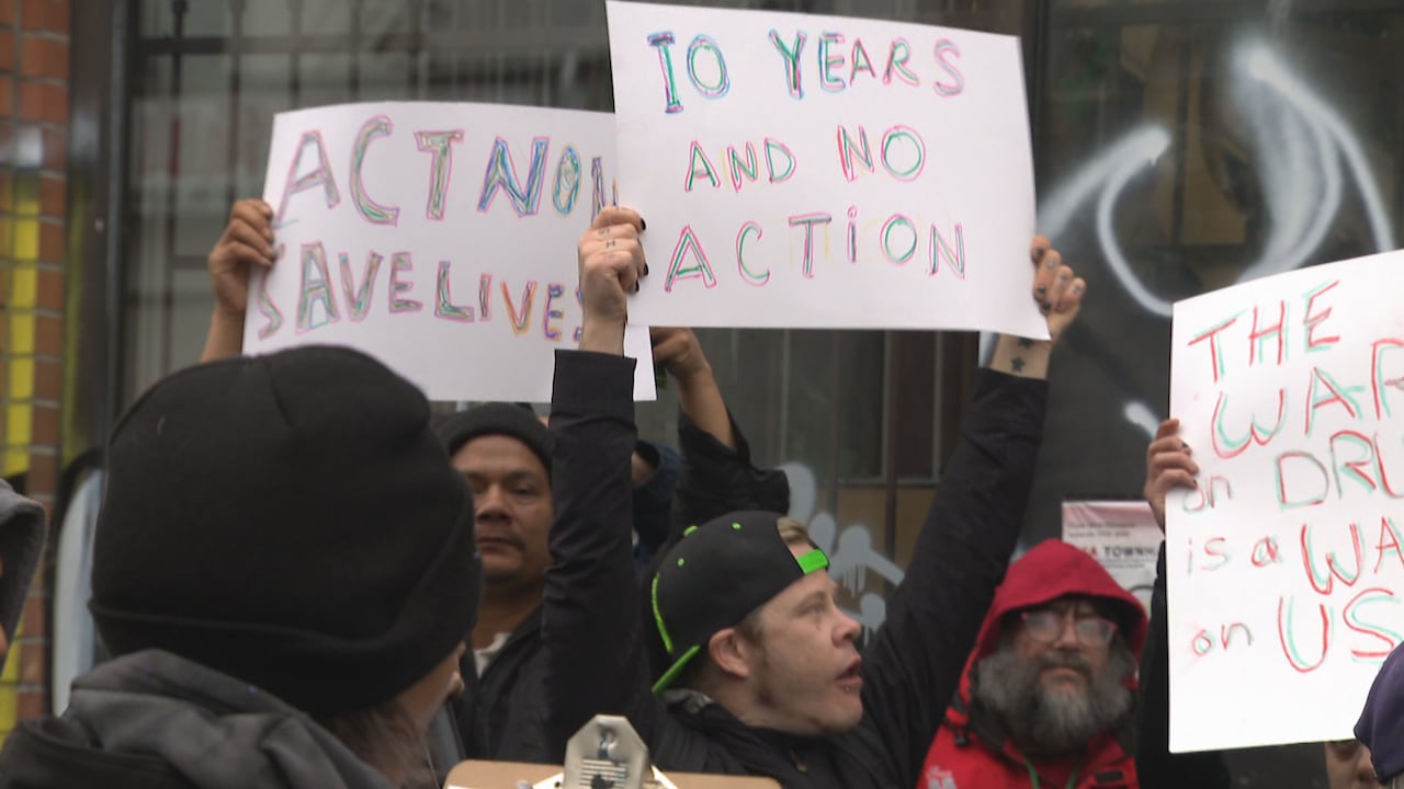 People hold up signs at a rally reading 'Act now save lives' and '10 years no action'.