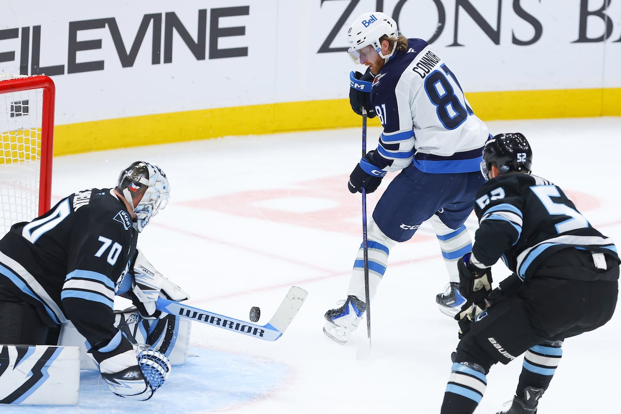 A Jets player shoots the puck on his forehand toward Utah's goalie.