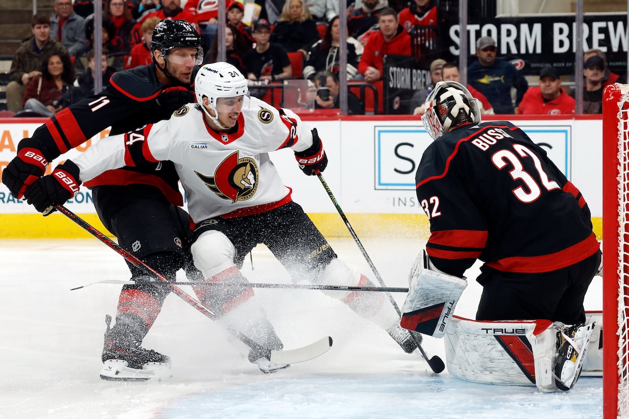 A hockey player comes to a sudden stop right in front of an opposing goalie during a game.