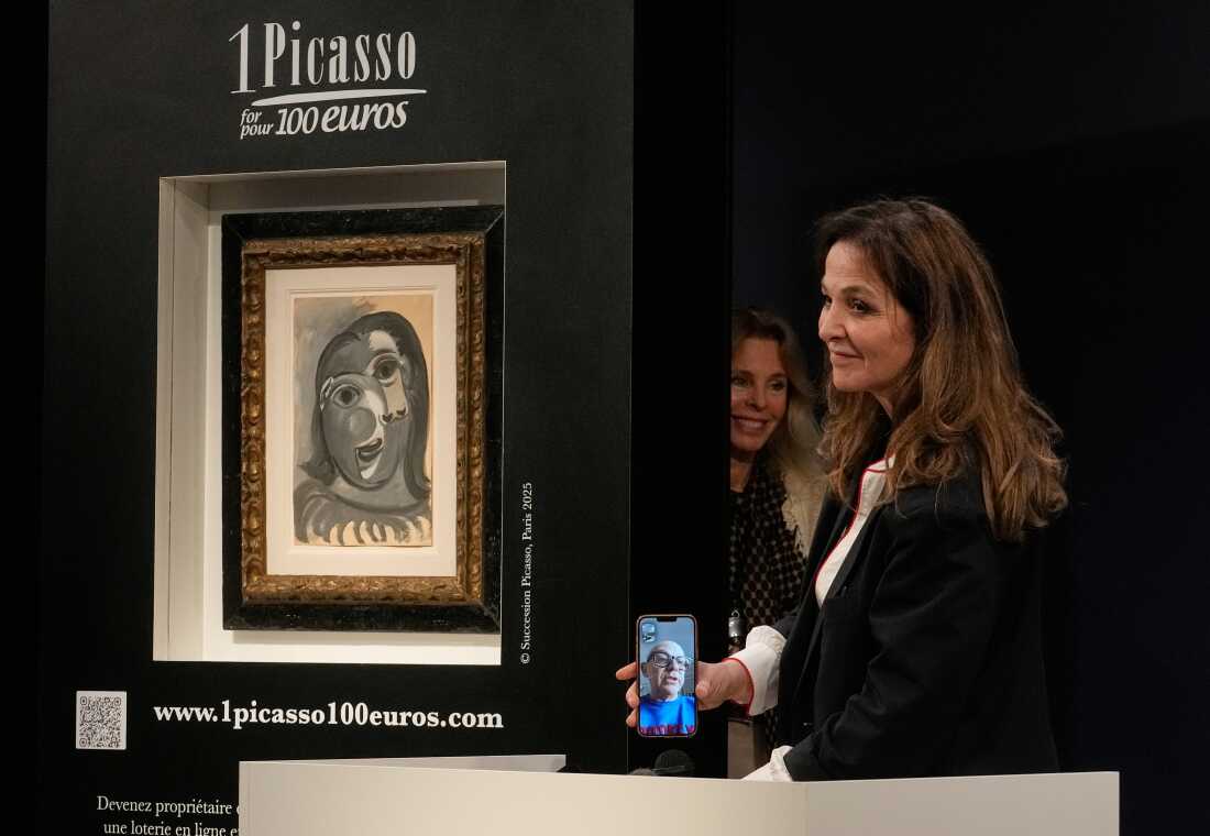 Peri Cochin, right, founder of "1 Picasso for 100 euros," speaks on the phone with the winner, Ari Hodara of Paris, next to the painting 'Head of a Woman' by Pablo Picasso, painted in 1941, after the raffle draw at Christie's in Paris, Tuesday, April 14, 2026, in support of Alzheimer's research.
