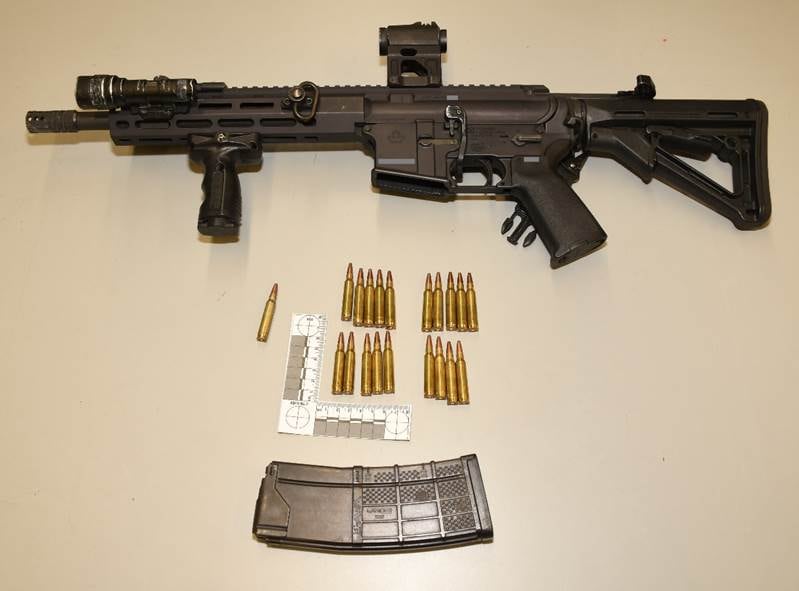A rifle with ammunition laid out on a table.