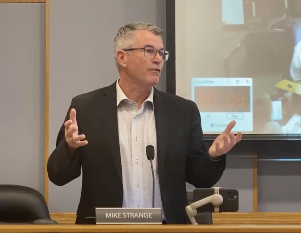 man in suit stands at microphone