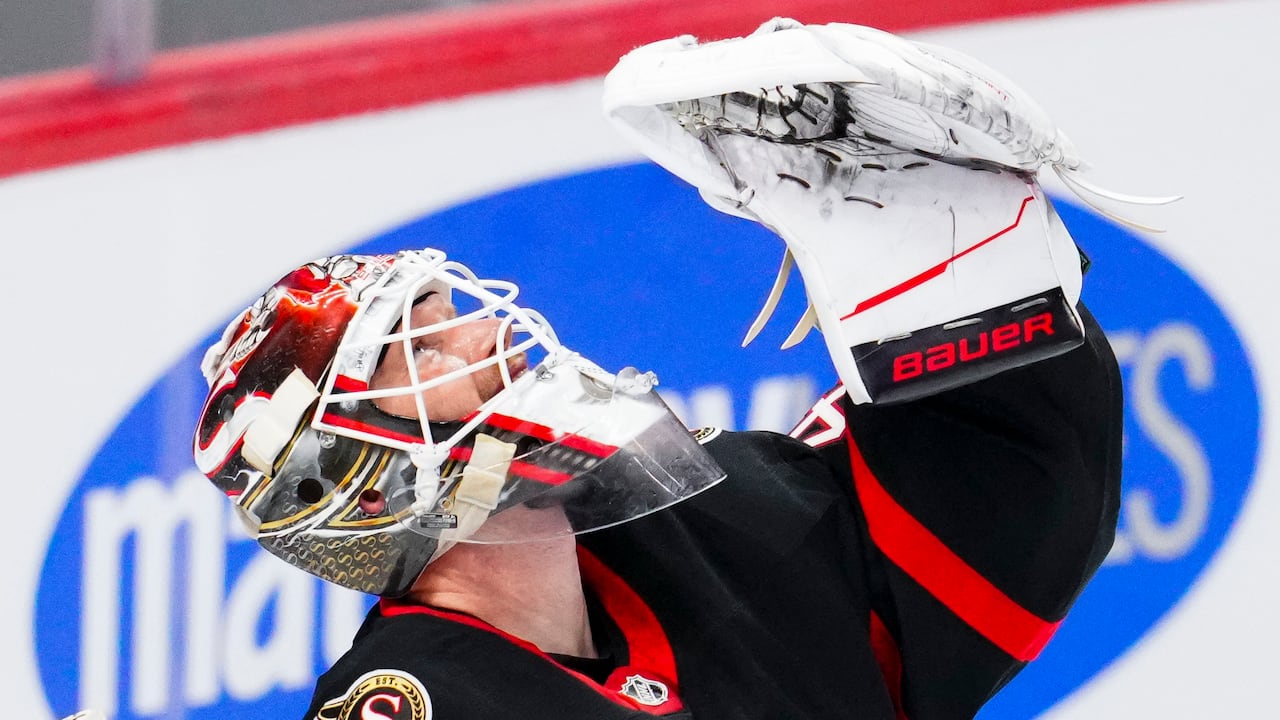A hockey goaltender raises his glove in celebration after a win.