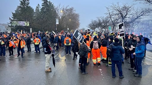 A crowd of workers stand on a Montreal street