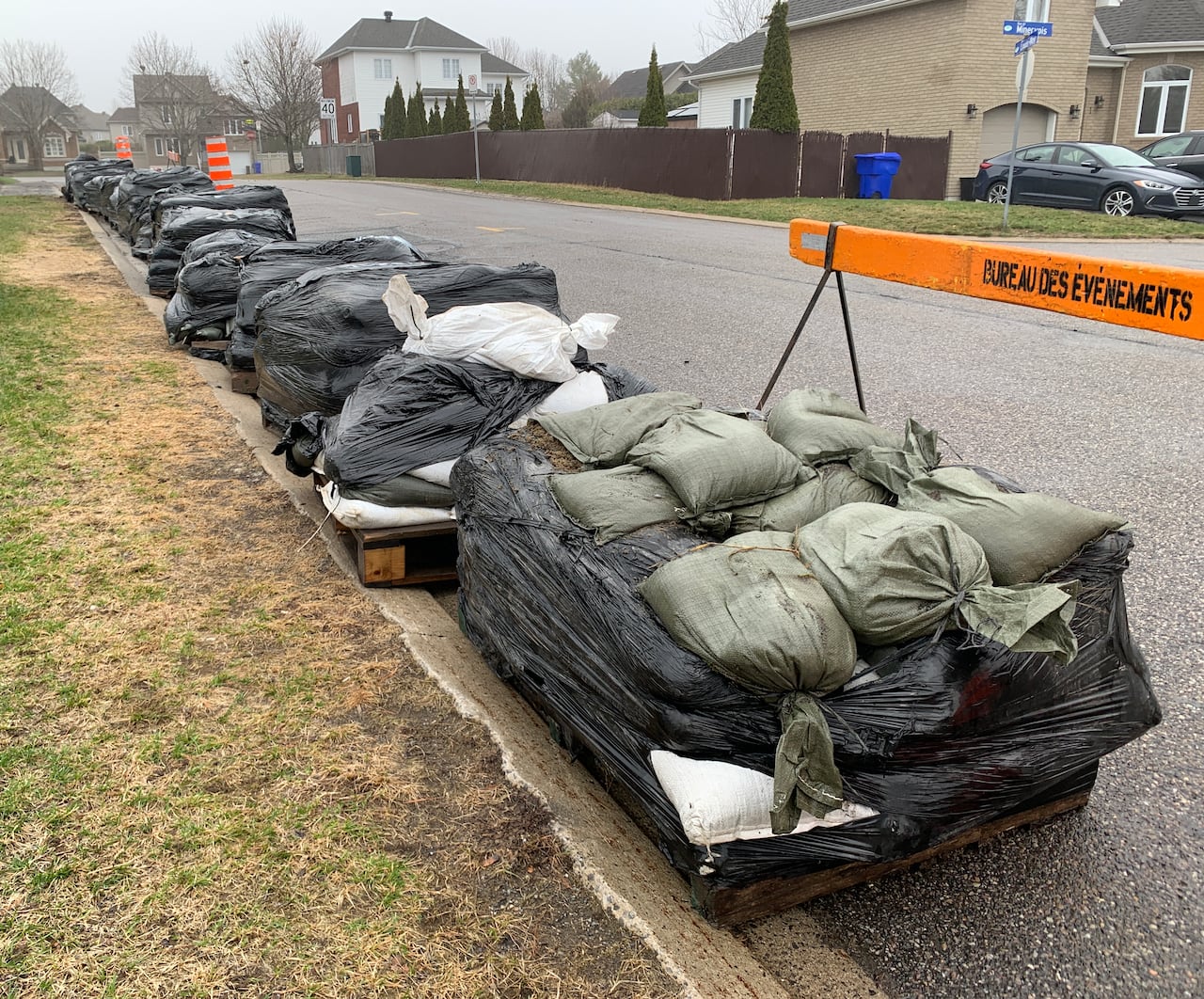 Piles of sandbags on a residential street on a rainy spring day.