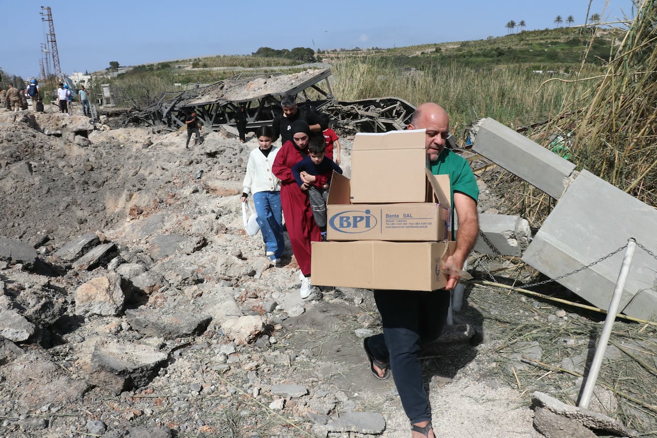 People cross on foot next to a destroyed bridge.