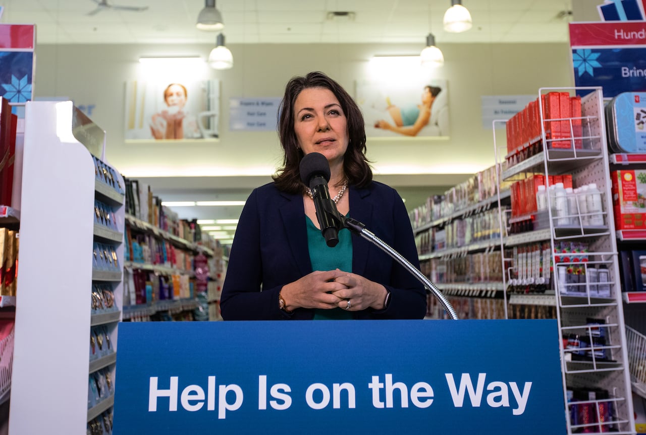 A woman stands behind a podium that reads, "Help is on the way."