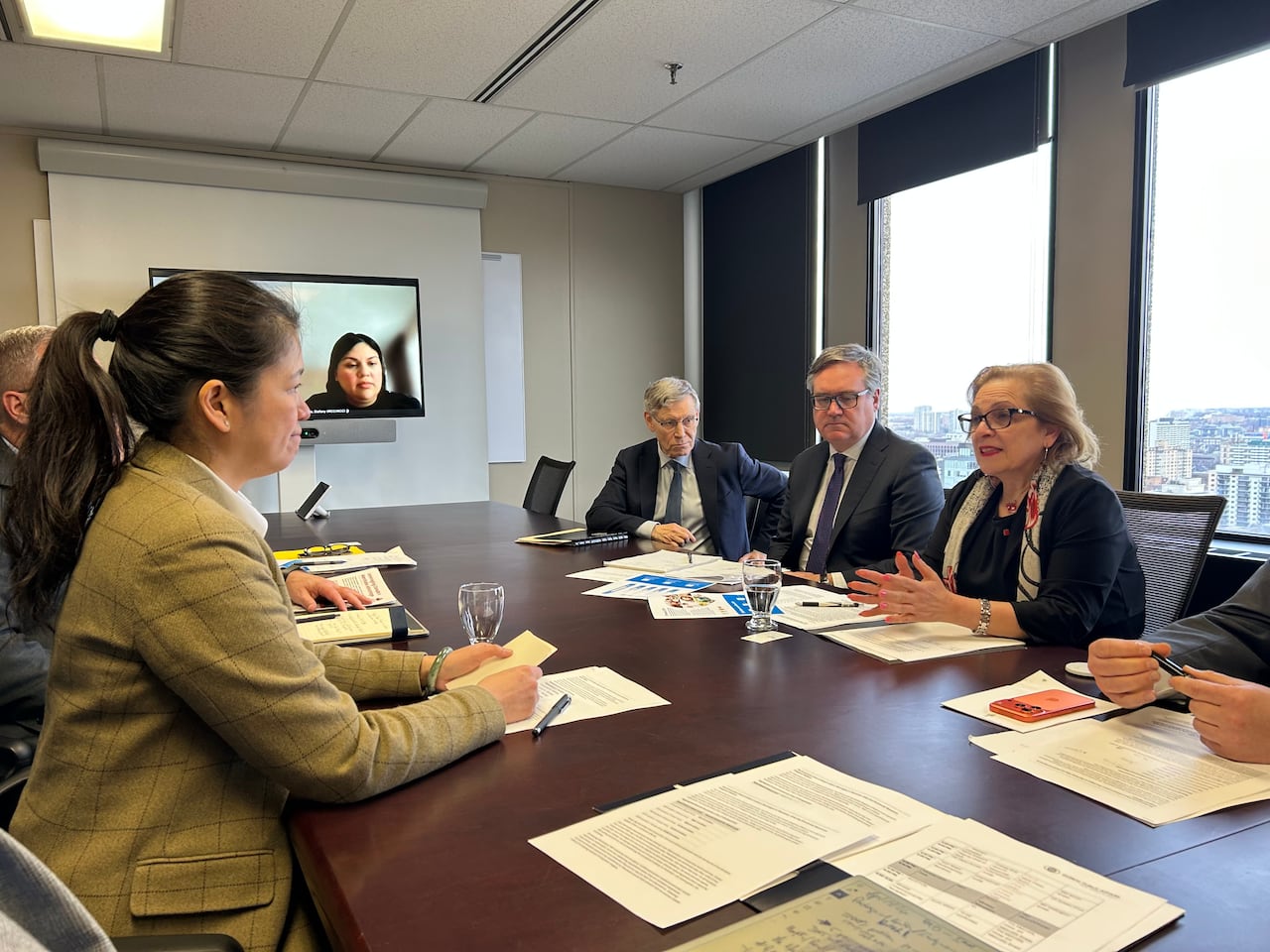 Two women have an exchange at a board table.