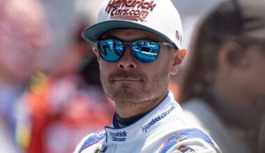 NASCAR driver Kyle Larson looking into the distance with sunglasses and a Hendrick Motorsports cap