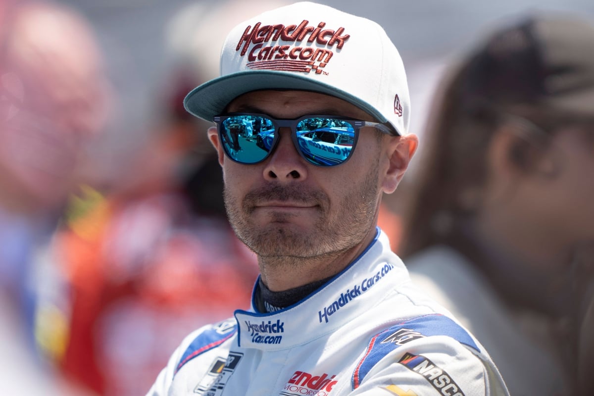 NASCAR driver Kyle Larson looking into the distance with sunglasses and a Hendrick Motorsports cap