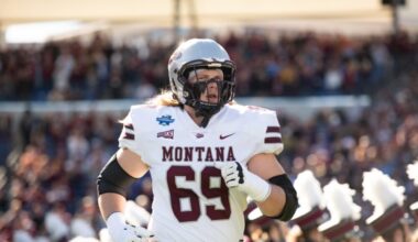 Montana football player wearing number 69 in a white uniform runs on the field during a game with a crowded stadium in the background