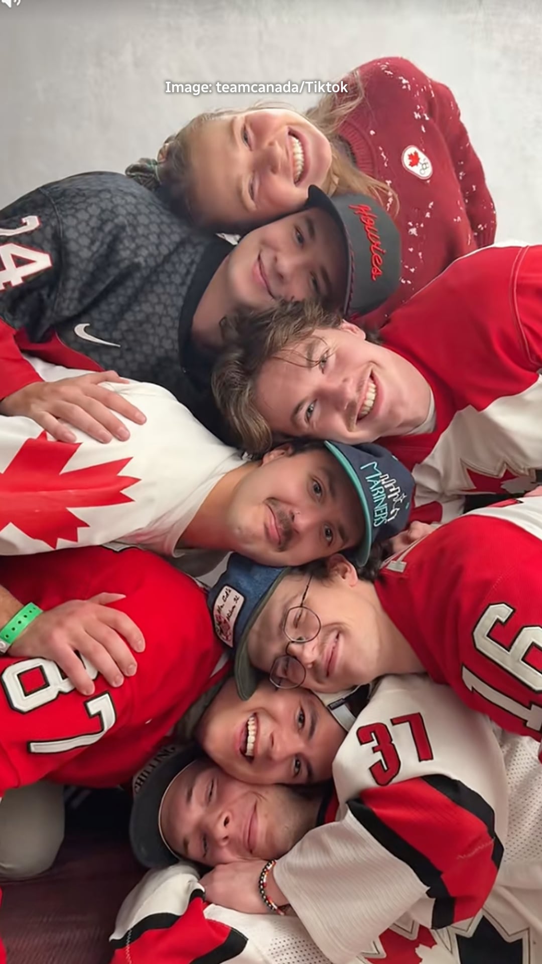 a group of six guys and a woman make a pyramid with their faces