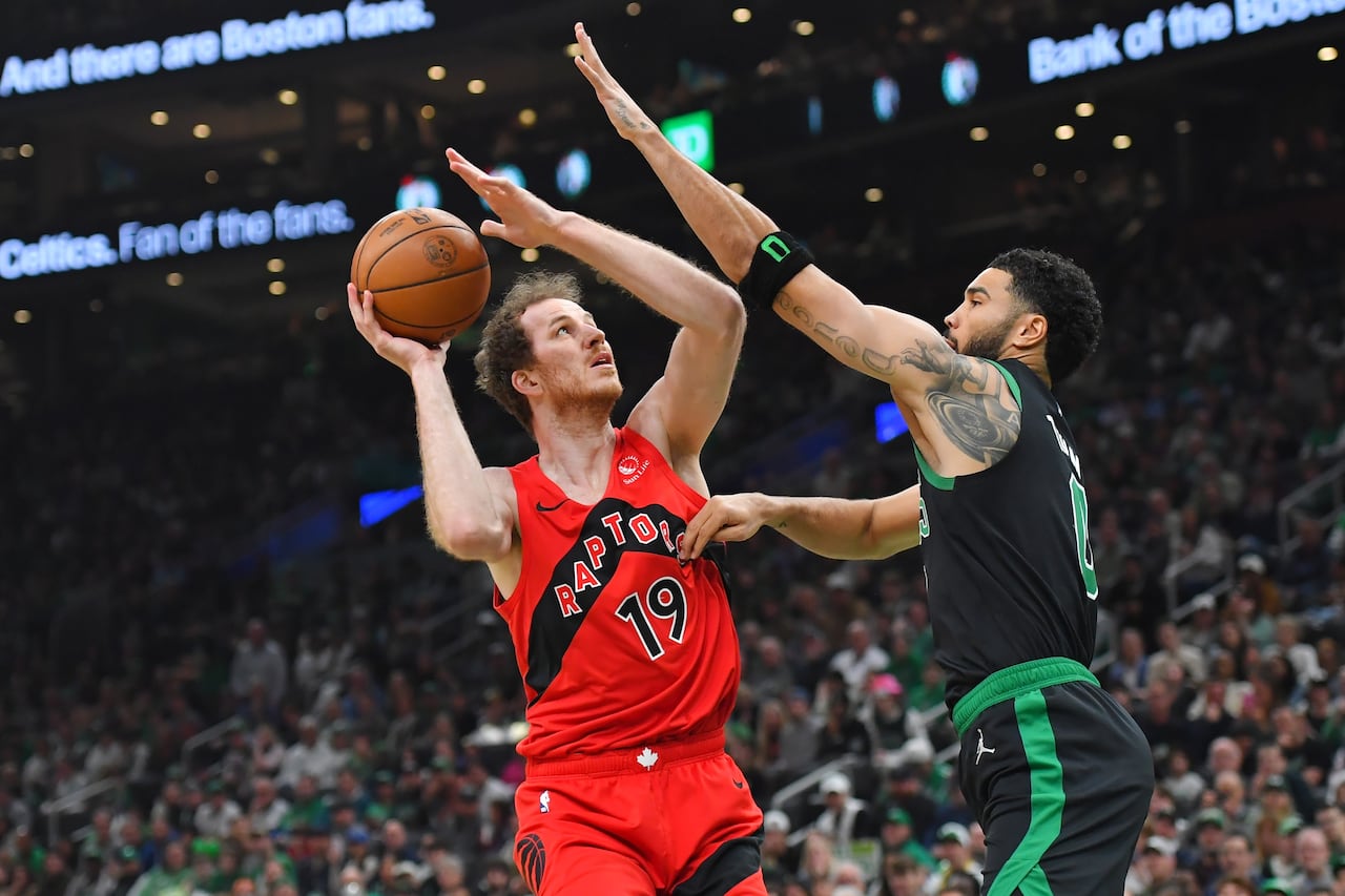 Jakob Poeltl of the Toronto Raptors makes a shot while Boston Celtics forward Jayson Tatum defends against that effort