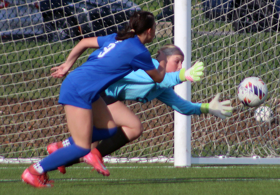 Roxana goalie Sydney Ufert makes a save while being pressured by Remmi Copeland of Marquette Friday at Glazebrook Park in Godfrey.