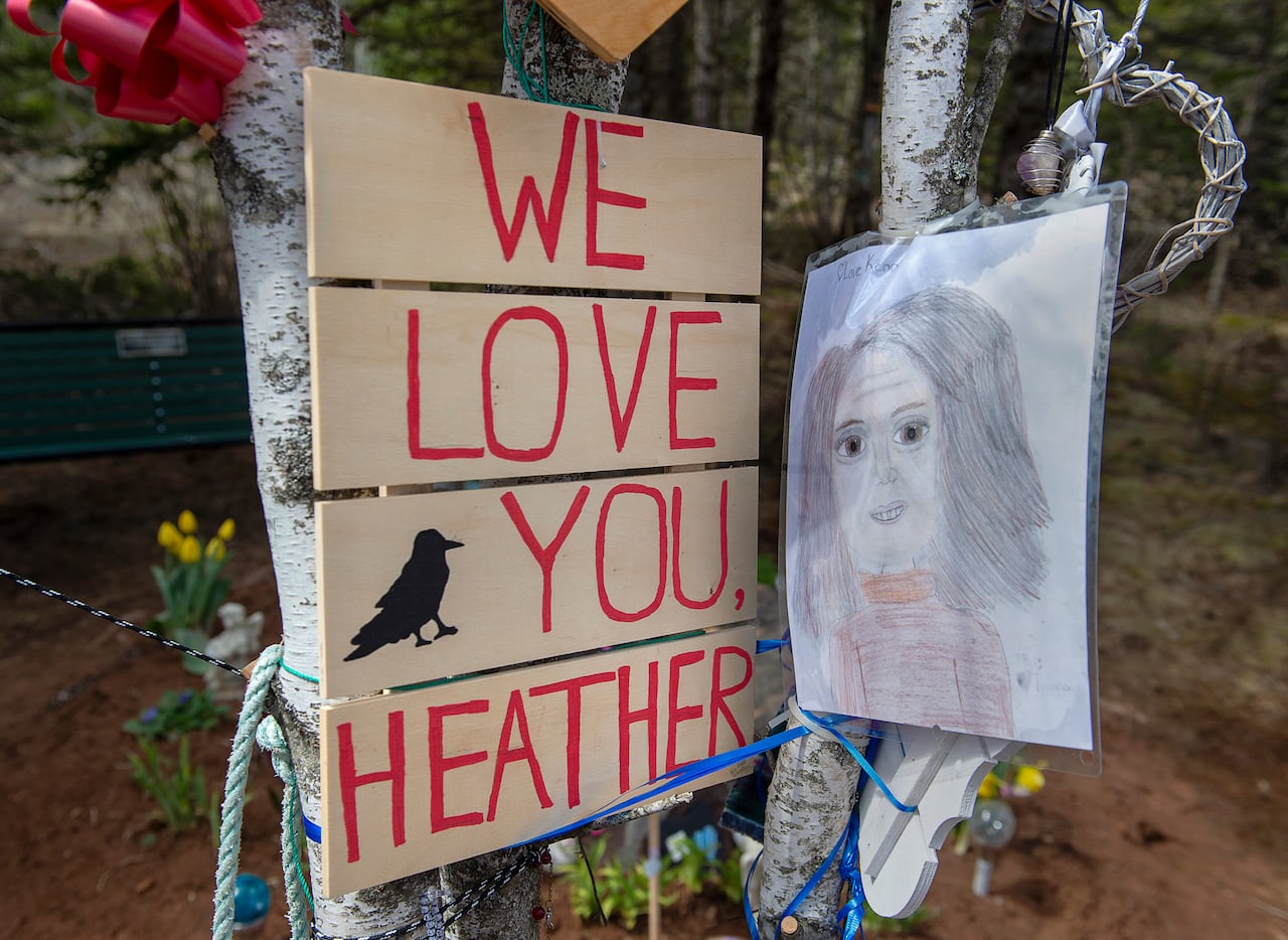 A sign and a hand-drawn picture attached to trees.