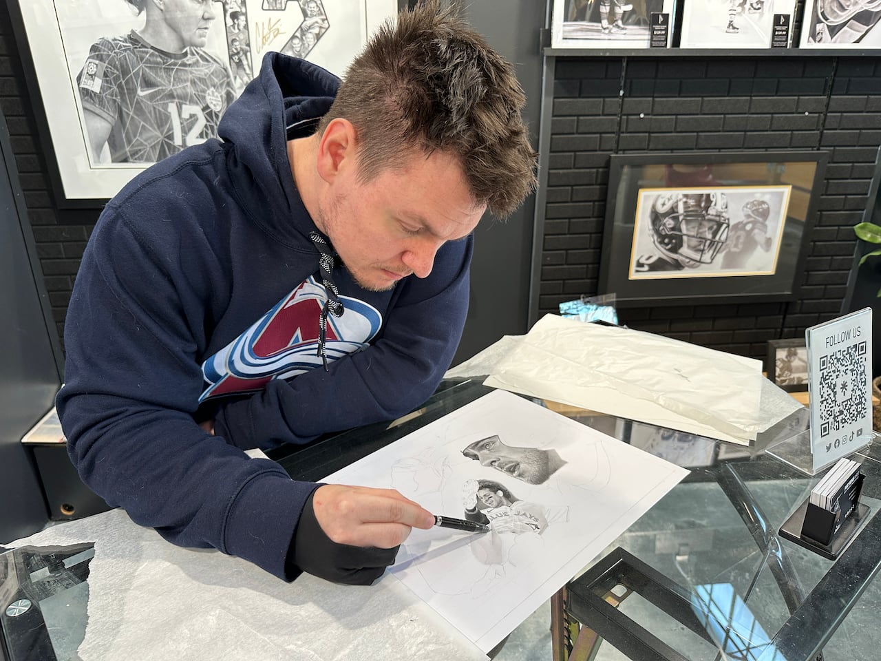 An artist draws a baseball player on a white sheet of paper.