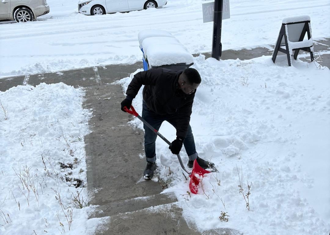 A man shovels snow from a sidewalk.