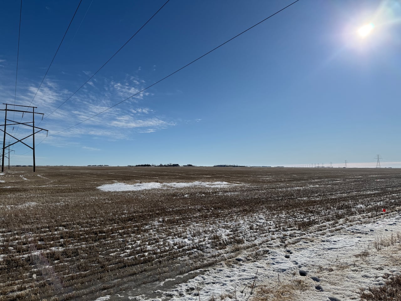An empty field is partially covered by snow.