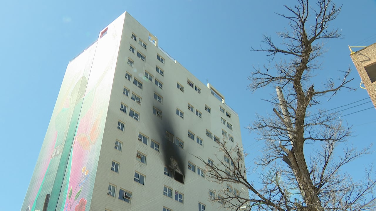 An apartment building. There's smoke marks coming out from an open window, going several floors up.