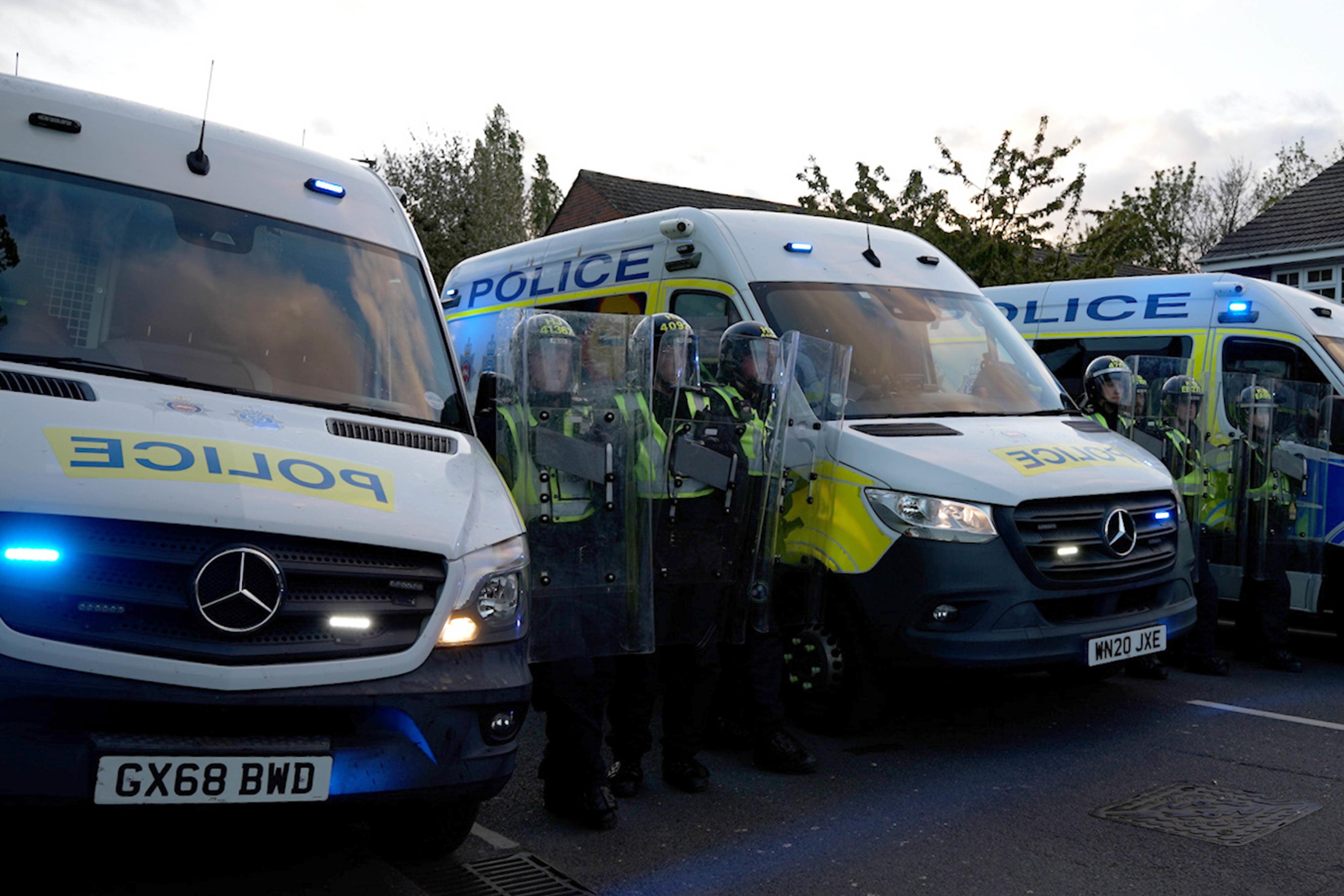 Officers wearing riot gear standing in between police vans in Epsom