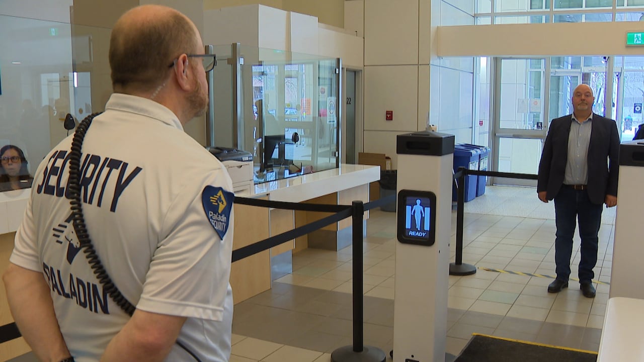 A mean wearing jeans, a dress shirt and a blazer prepares to go through a security screening.