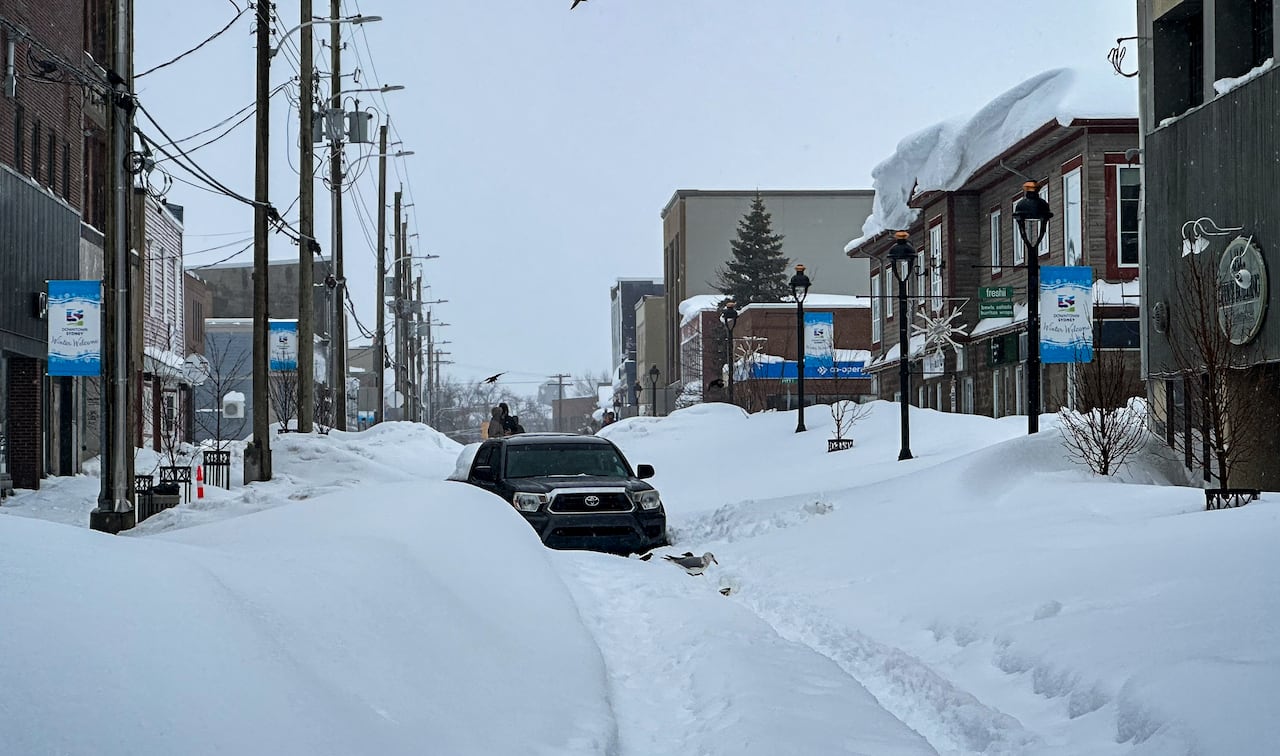 A car is stuck in a snowy city street.