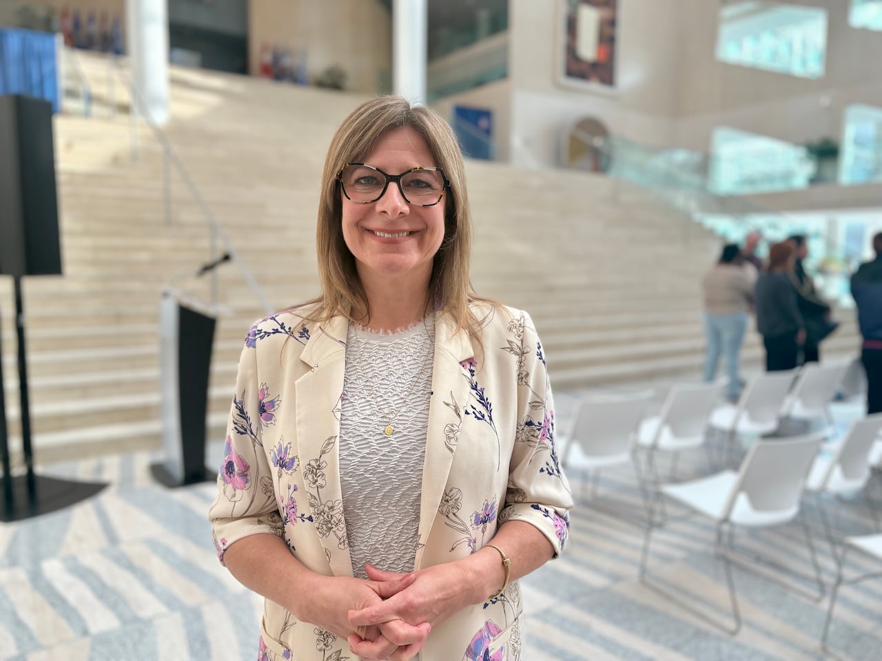 Woman smiles with folded hands.