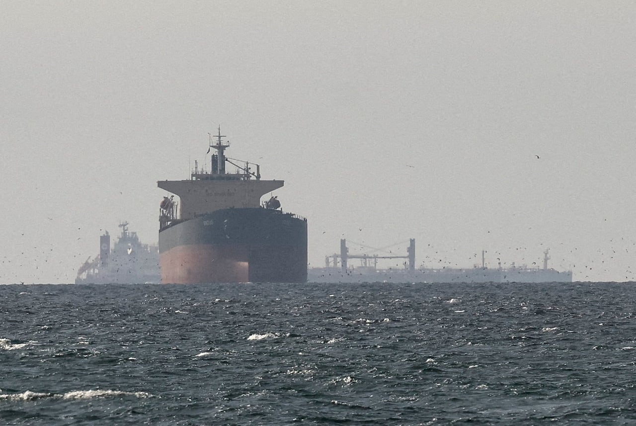 Large cargo ships are seen sailing on a large body of water.