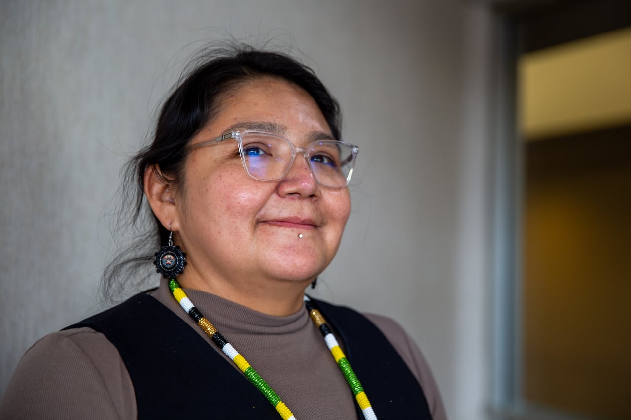 A close-up of a person wearing glasses and a beaded medallion around their neck.