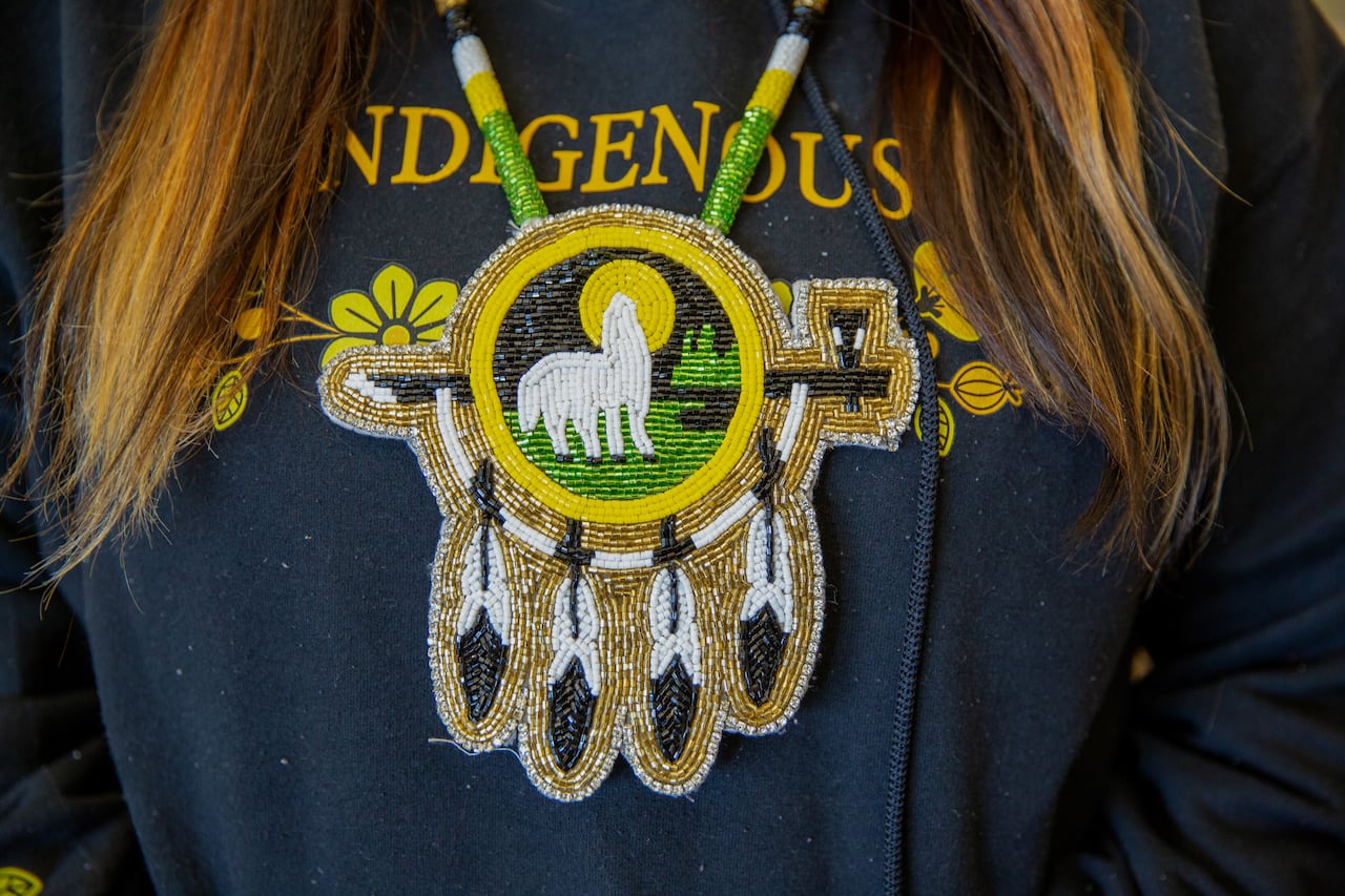 A close-up of a beaded medallion featuring a wolf howling at the moon.