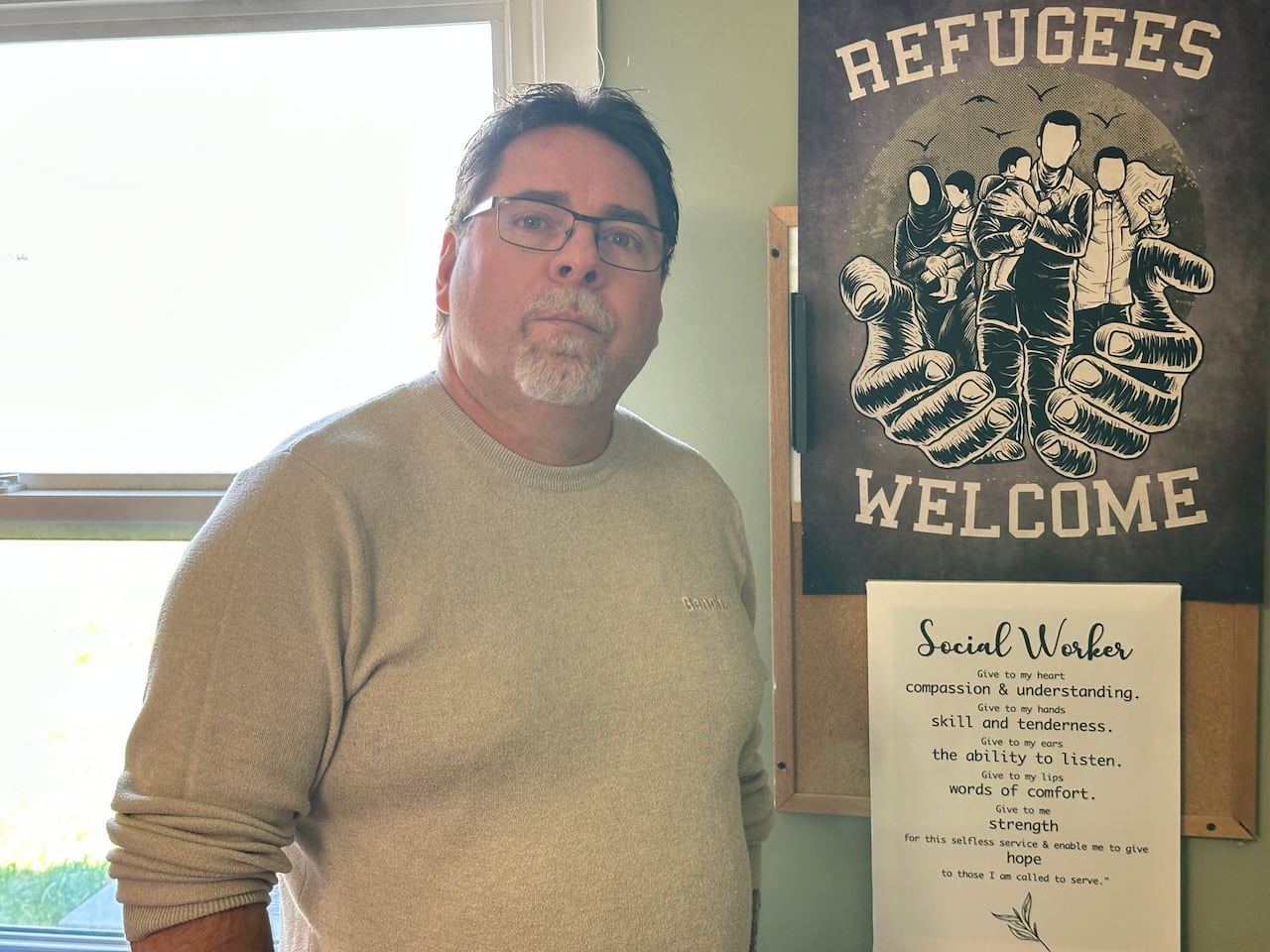 A man standing next to a 'Refugees Welcome' signage