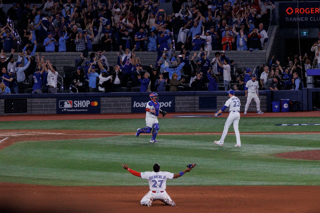 Baseball players on the field celebrating with cheering crowd near home plate.