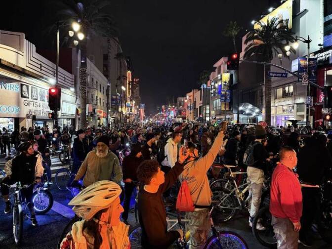 Thousands of bike riders fill a street at night.