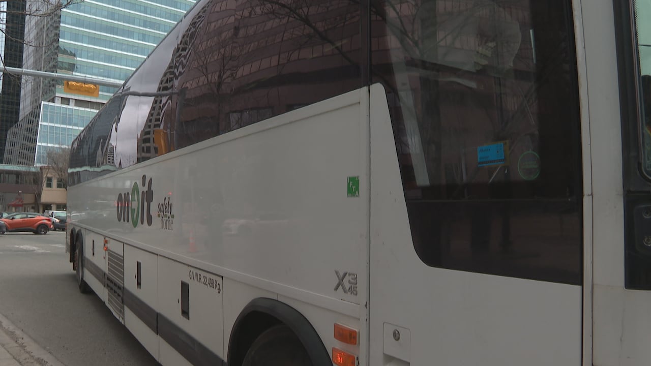 A motor coach parked on a downtown city street.