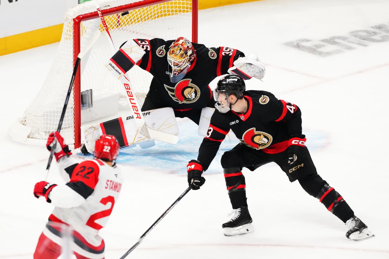 A hockey player scores a goal into a net