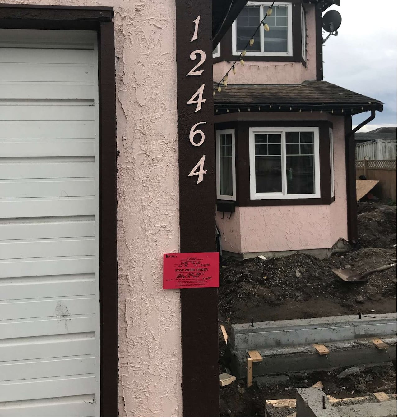 A red note hangs on the side of a garage, with construction clearly visible.