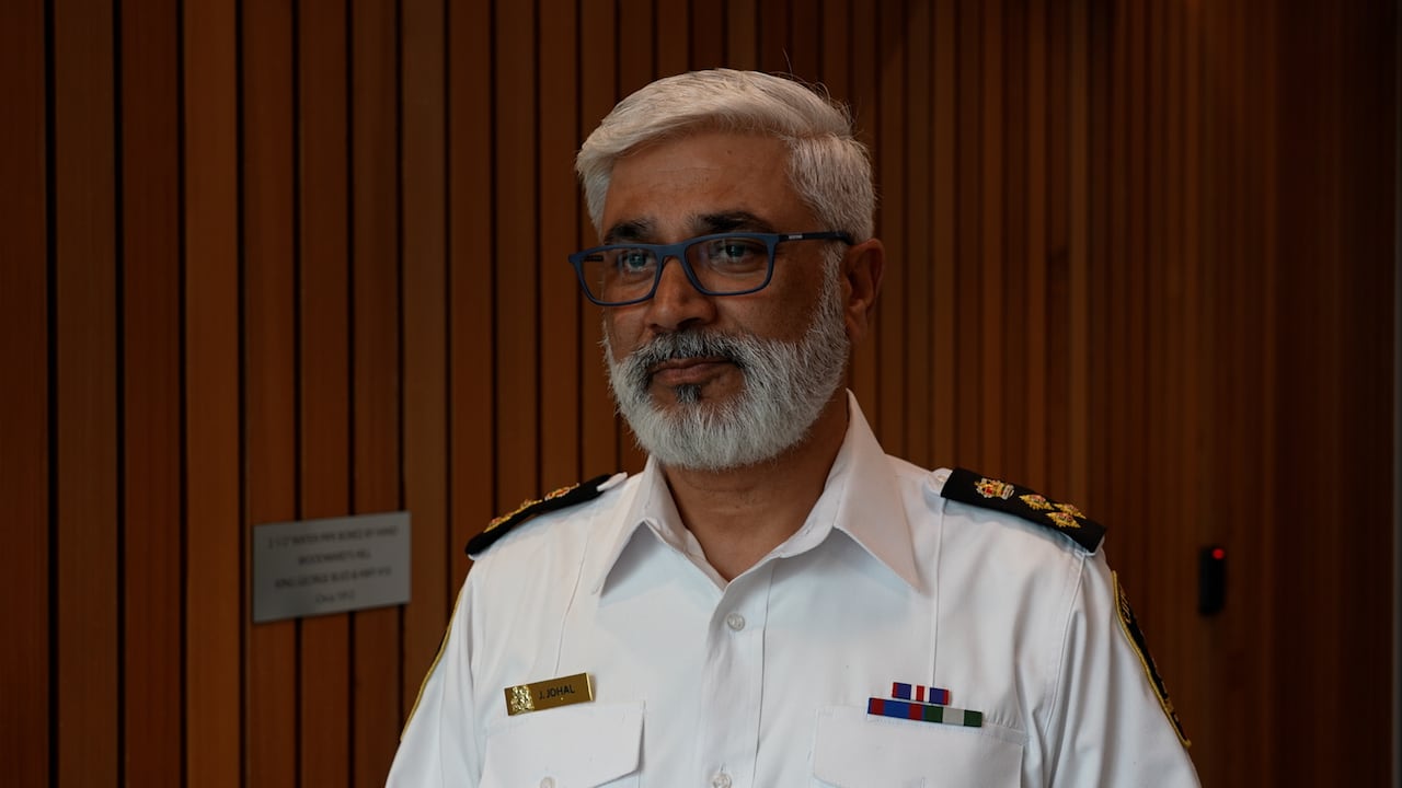 A bylaw officer wearing an official uniform looks on.