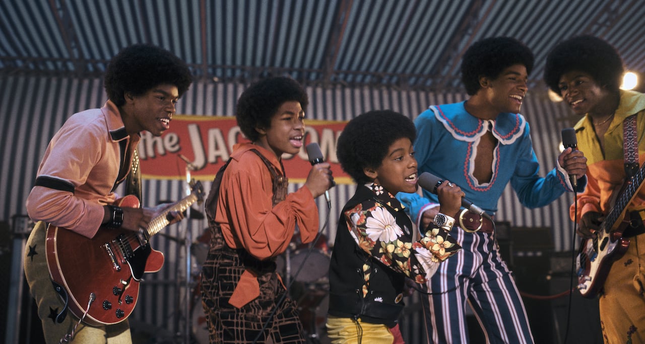 A group of young musicians wearing 60s-era outfits perform onstage.