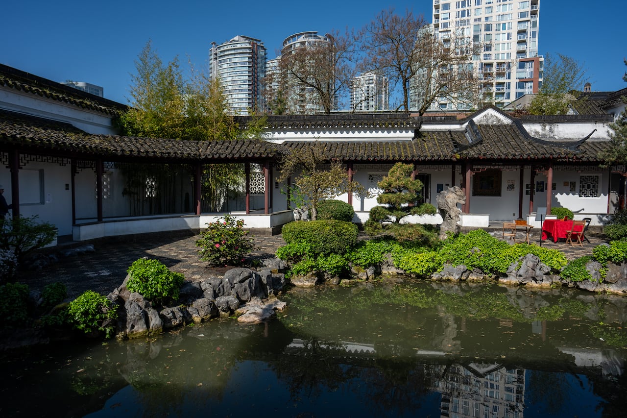 A pond is seen in the shadow of a classical Chinese-style home.