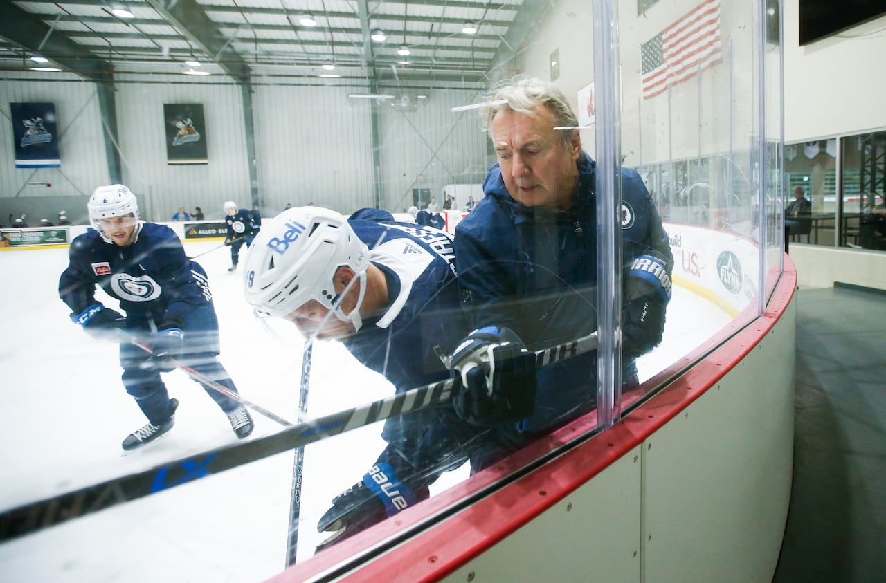 A coach with two hockey players at a rink