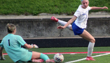 Alton goalie Lyla Cowan (1) slides out to make a save against Marquette's Alex Stephan during Friday's game at Public School Stadium.