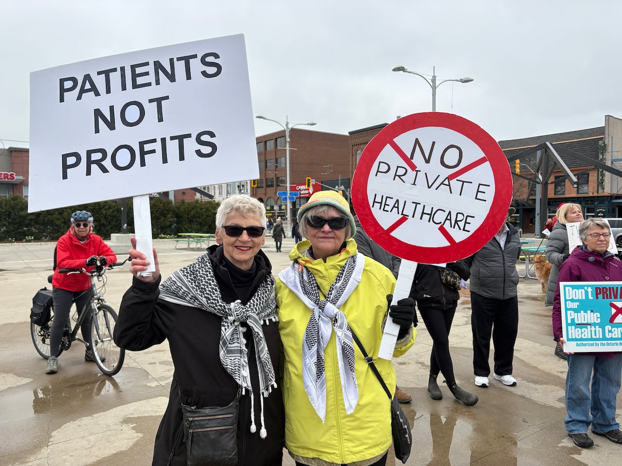 Person holding up sign against privatized healthcare with architectural structure in background