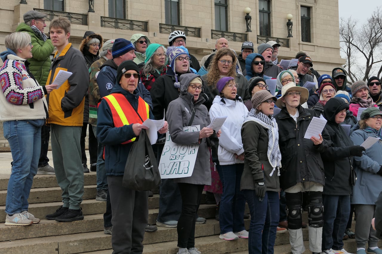 People singing while holding pieces of paper