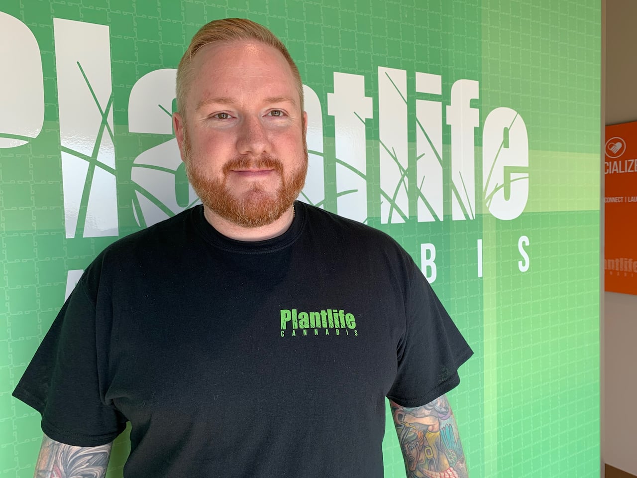 A man wearing a black T-shirt that says "Plantlife Cannabis."